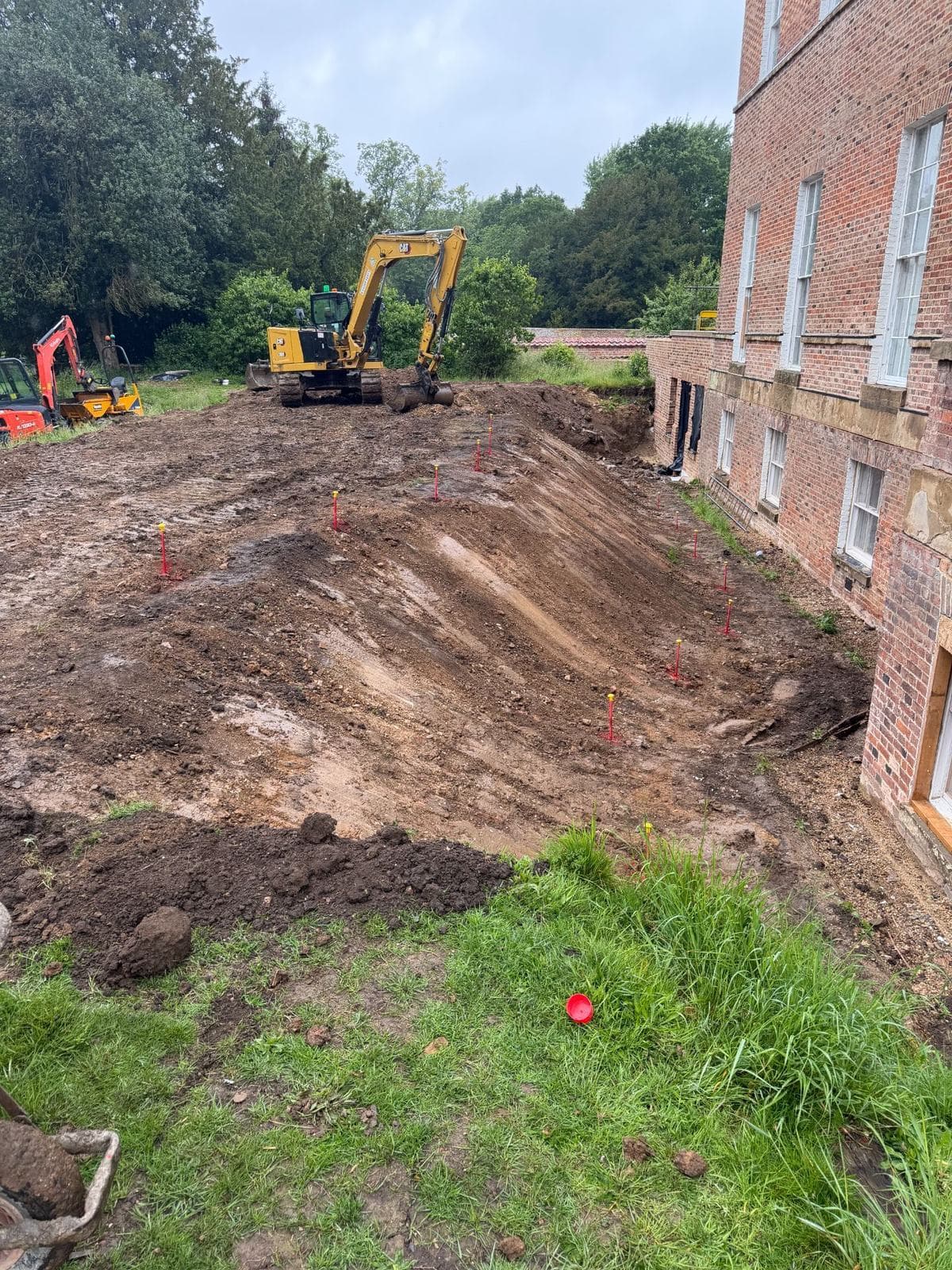 Reduced-level excavation running along the flank of the Georgian brick hall
