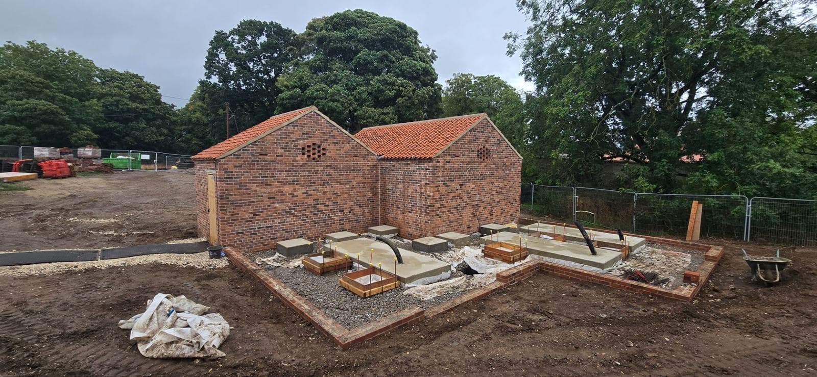 Completed reinforced concrete pad foundations and ground beams inside a restored brick outbuilding