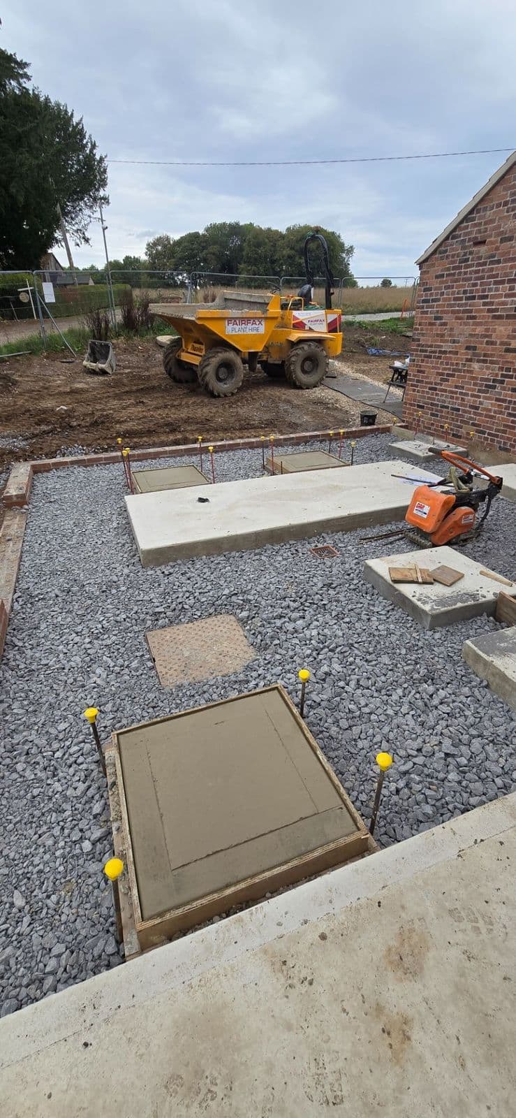 Foundation-stage groundworks alongside an existing red brick range
