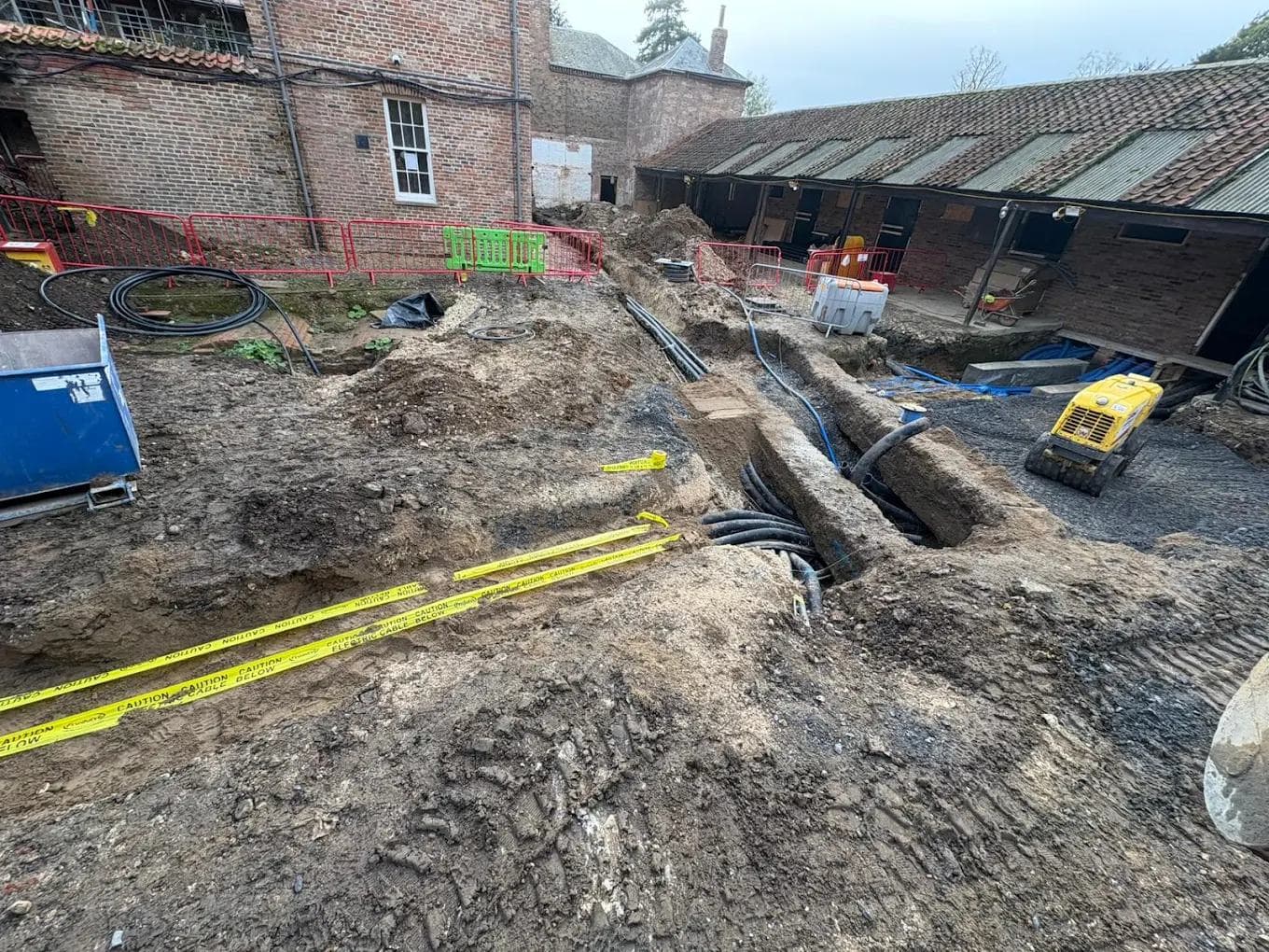 Courtyard excavation with ducting laid and a mini excavator working