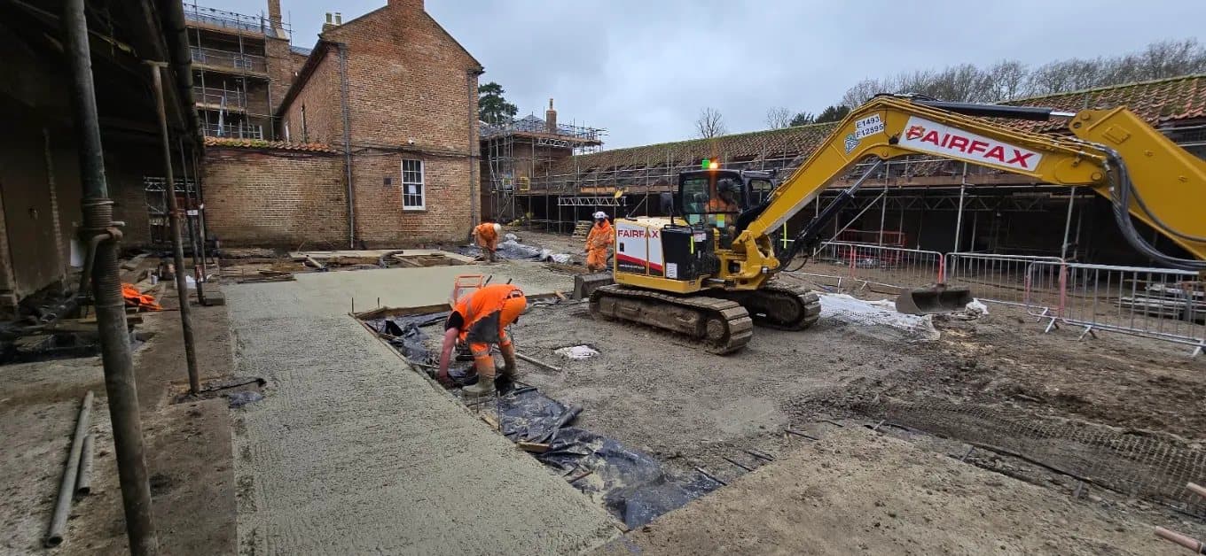Crew and excavator working on the finished courtyard slab
