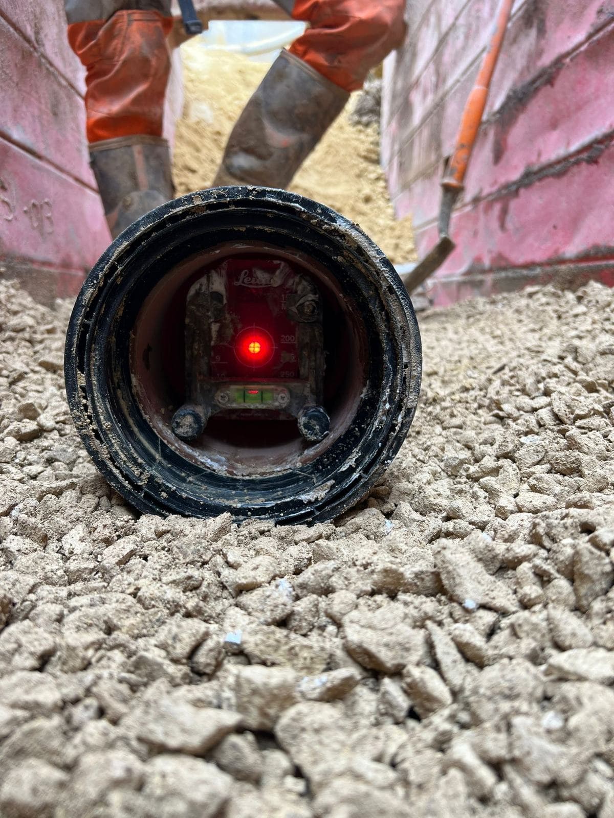 Pipe laser set in a pipe run to give line and level, in a supported trench on a stone bed